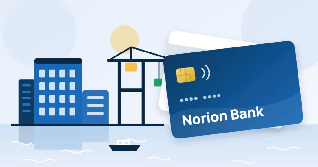 Ritat kreditkort med texten Norion Bank och ett vitt kort bakom, framför kontorshus och en hamnkran vid vattnet.